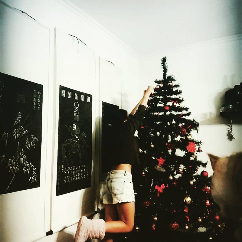 Татуированная девушка раздевается около рождественской елки дразня своим необычным телом 