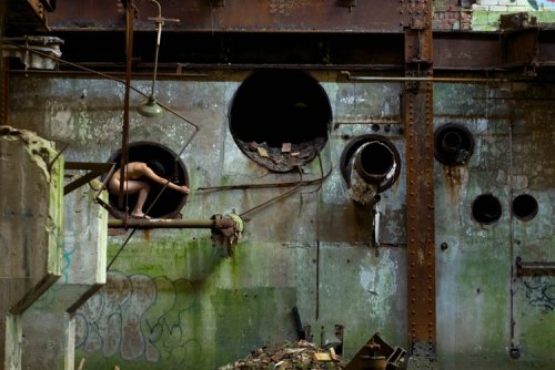 Обнаженная девушка посреди промышленных развалин