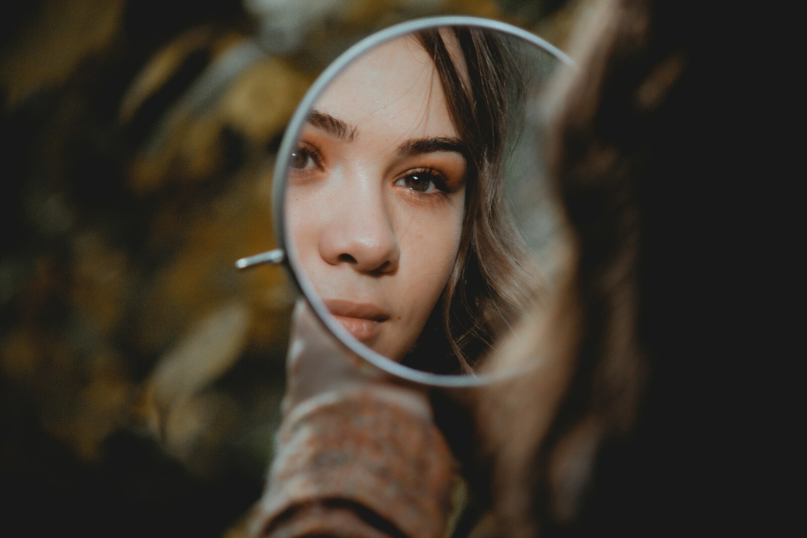 девушка смотрит в маленькое зеркальце